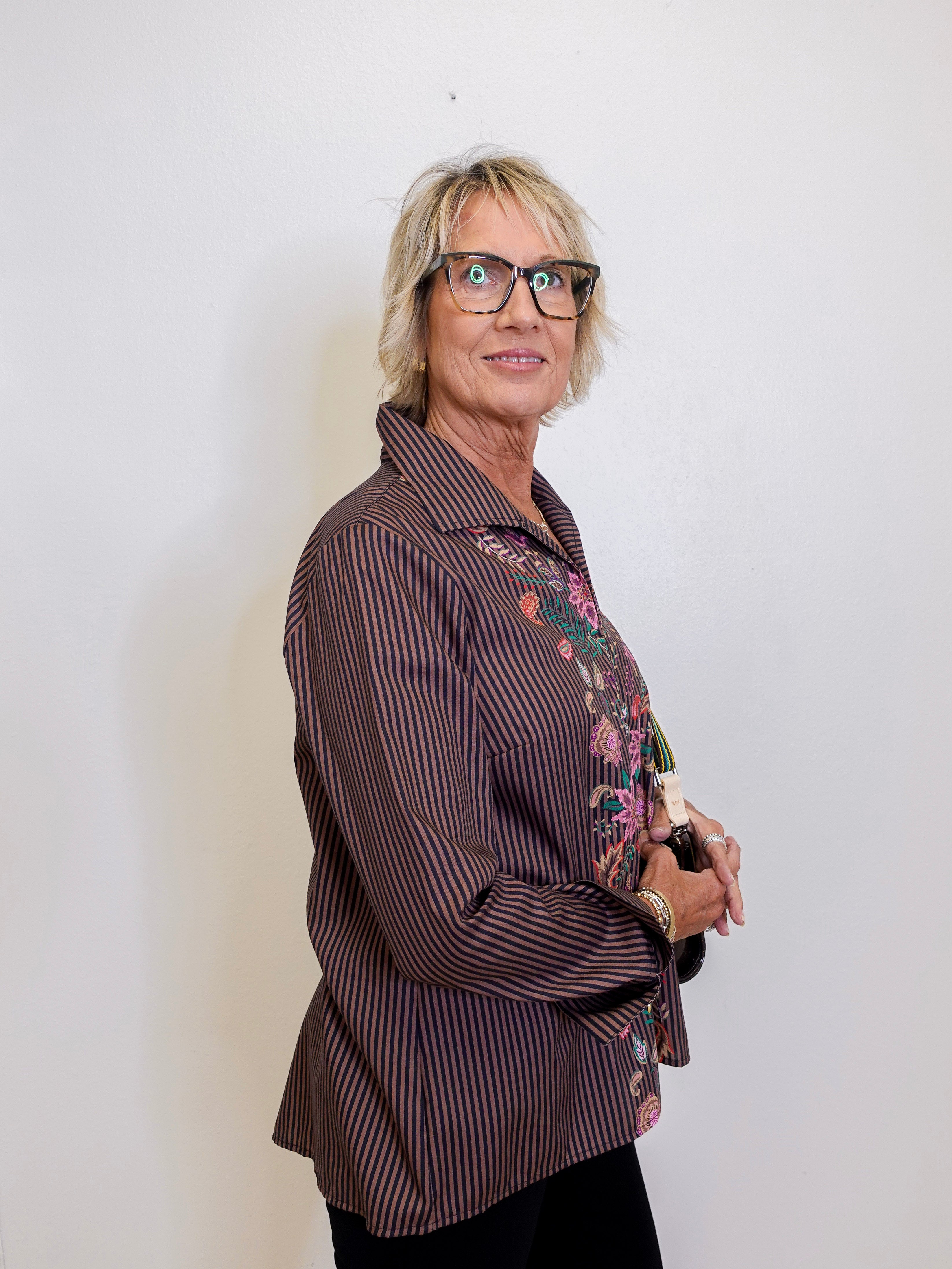 Woman wearing a brown striped shirt with floral patterns on a white background