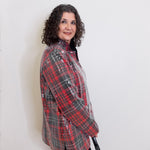 Woman wearing a red and gray plaid shirt against a white background