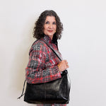 Woman holding a black leather bag against a white background