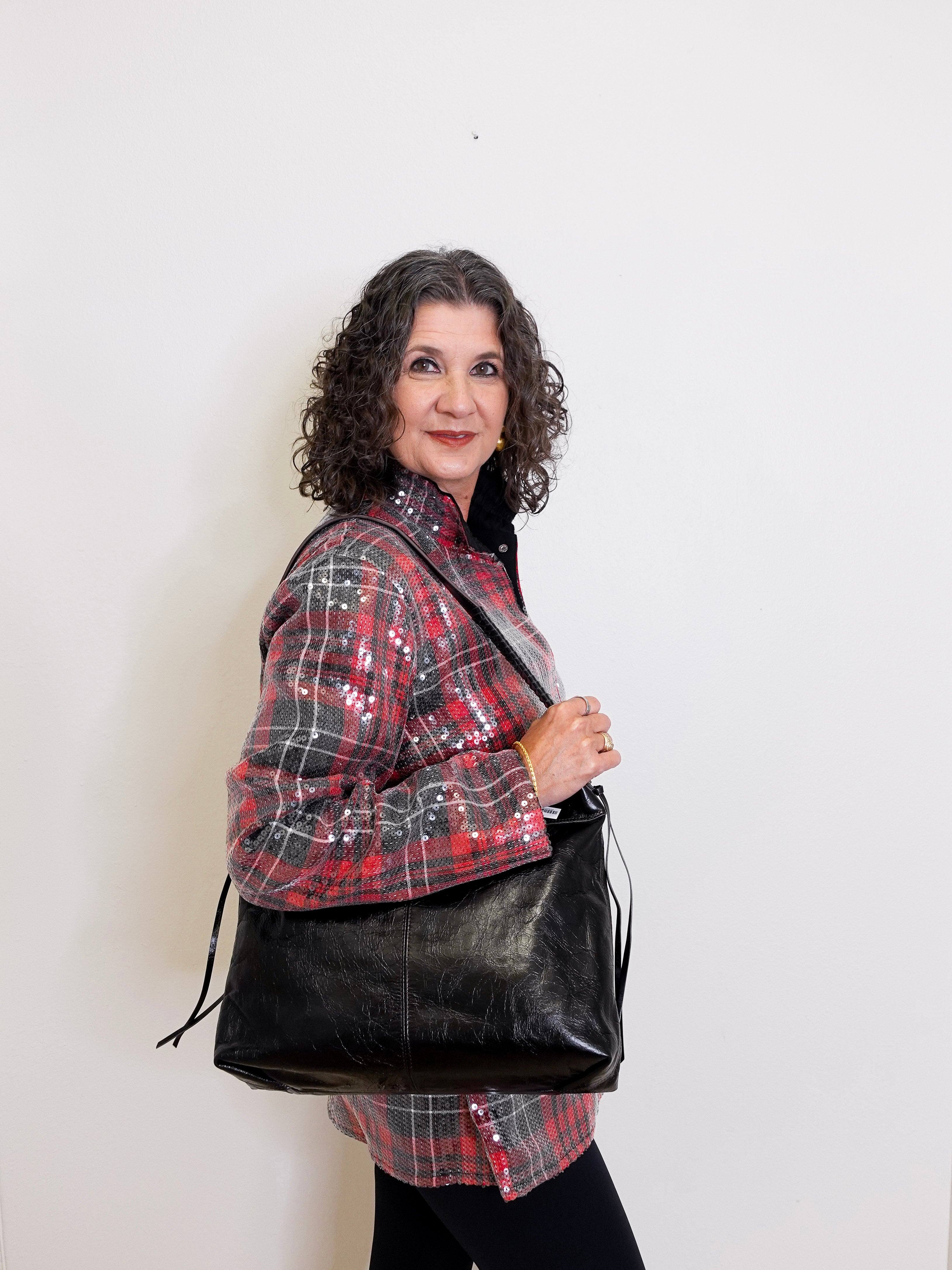 Woman holding a black leather bag against a white background