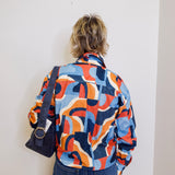 Person wearing a colorful patterned shirt against a plain background