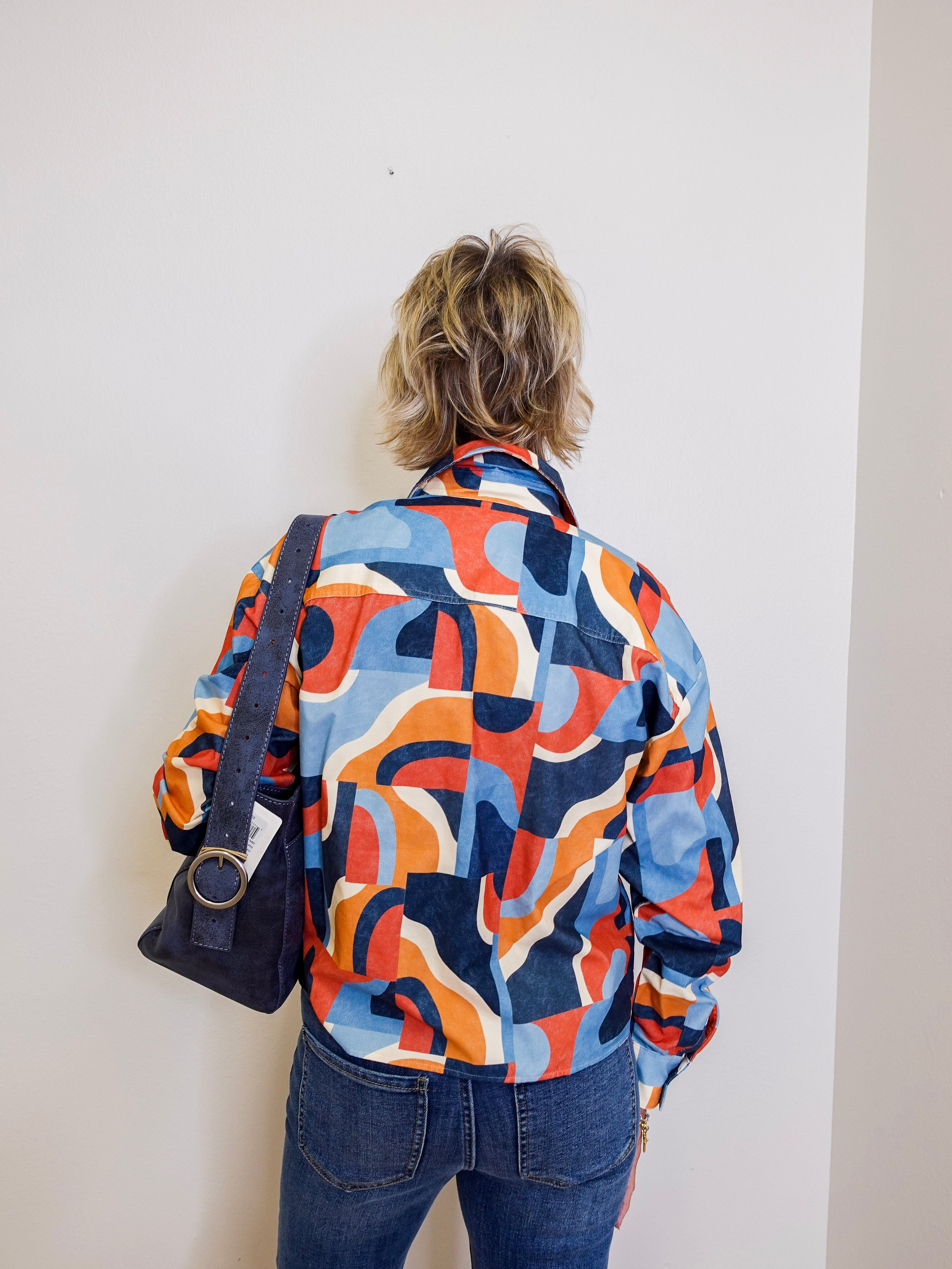 Person wearing a colorful patterned shirt against a plain background