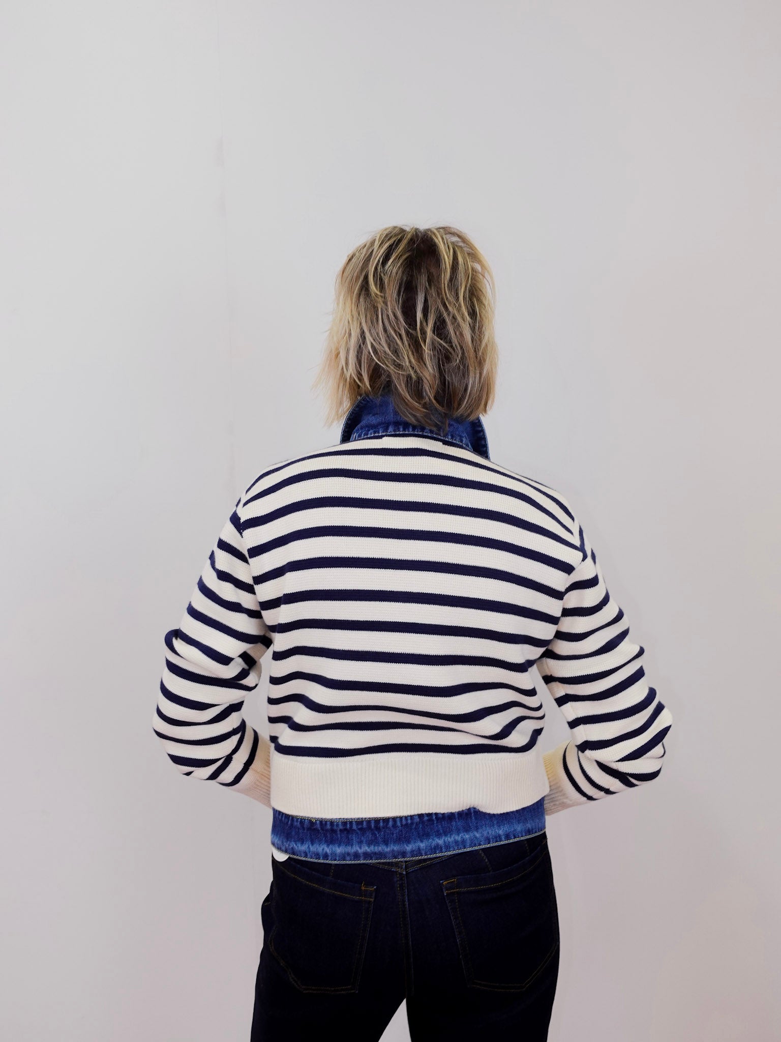 Person wearing a striped sweater with a plain background