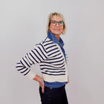 Person wearing a striped sweater and denim jacket against a plain background