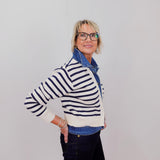Person wearing a striped sweater and denim jacket against a plain background