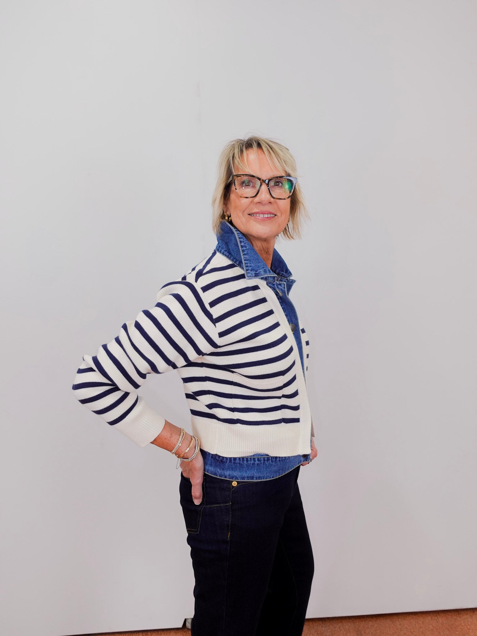 Person wearing a striped sweater and denim jacket against a plain background