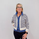 Woman wearing a striped cardigan over a denim shirt with a plain background