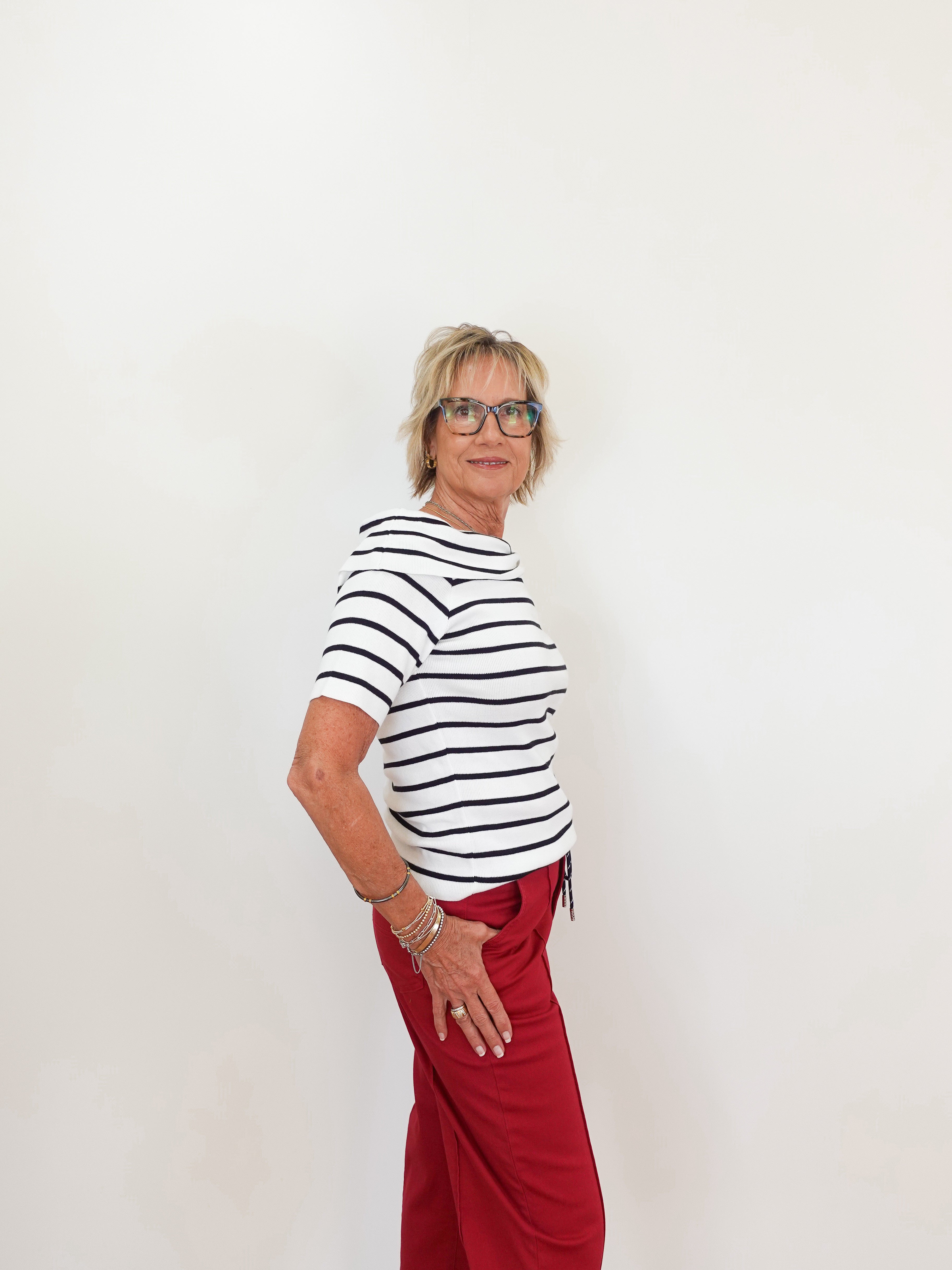 Woman wearing a black and white striped shirt and red pants against a white background