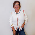 Woman wearing a white cardigan with colorful accents against a plain background