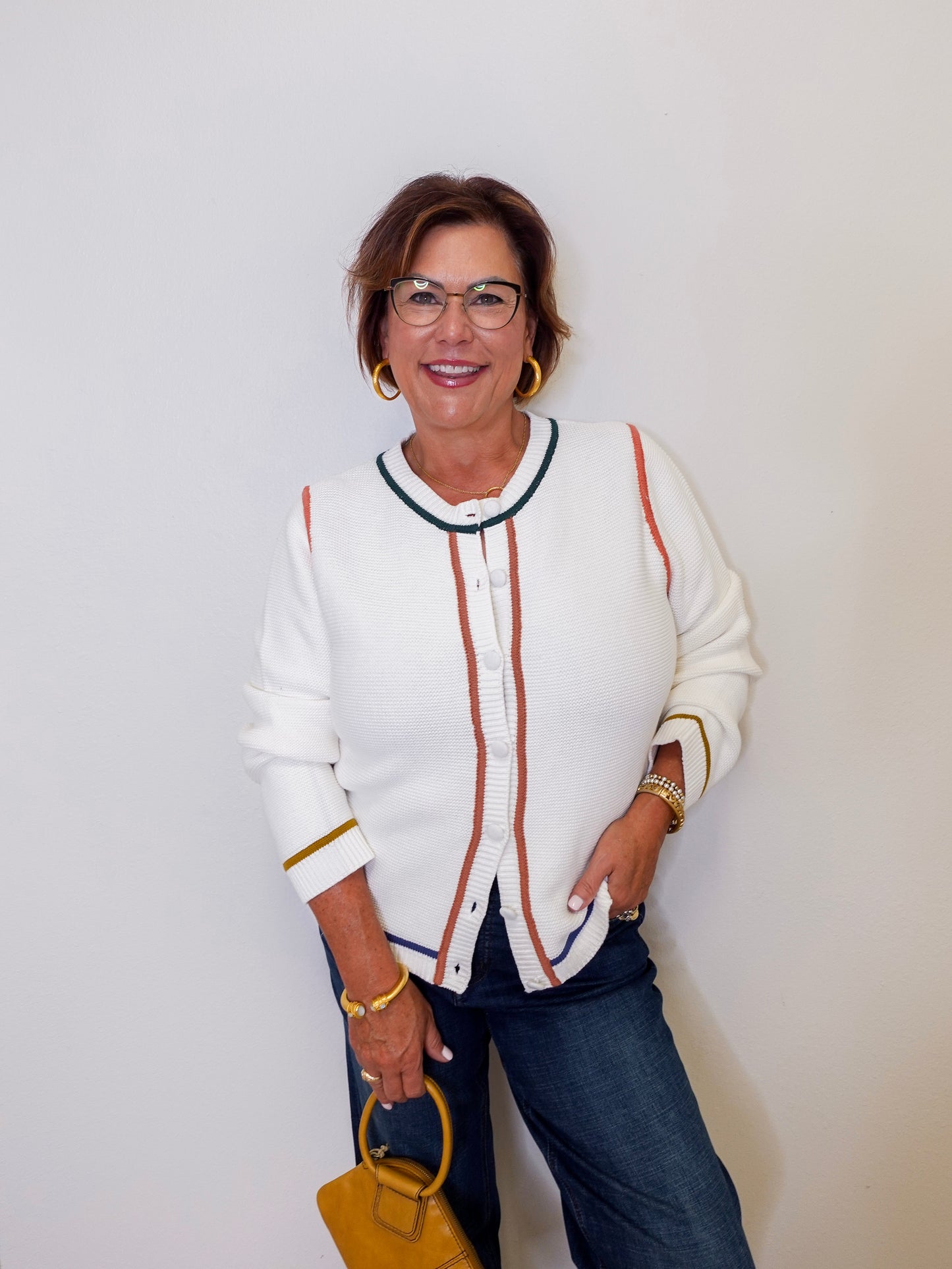 Woman wearing a white cardigan with colorful accents against a plain background