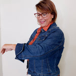 Woman wearing a blue denim jacket and orange shirt against a white background