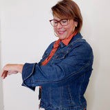 Woman wearing a blue denim jacket and orange shirt against a white background