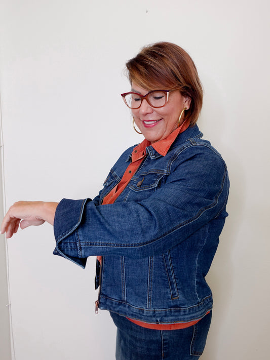 Woman wearing a blue denim jacket and orange shirt against a white background