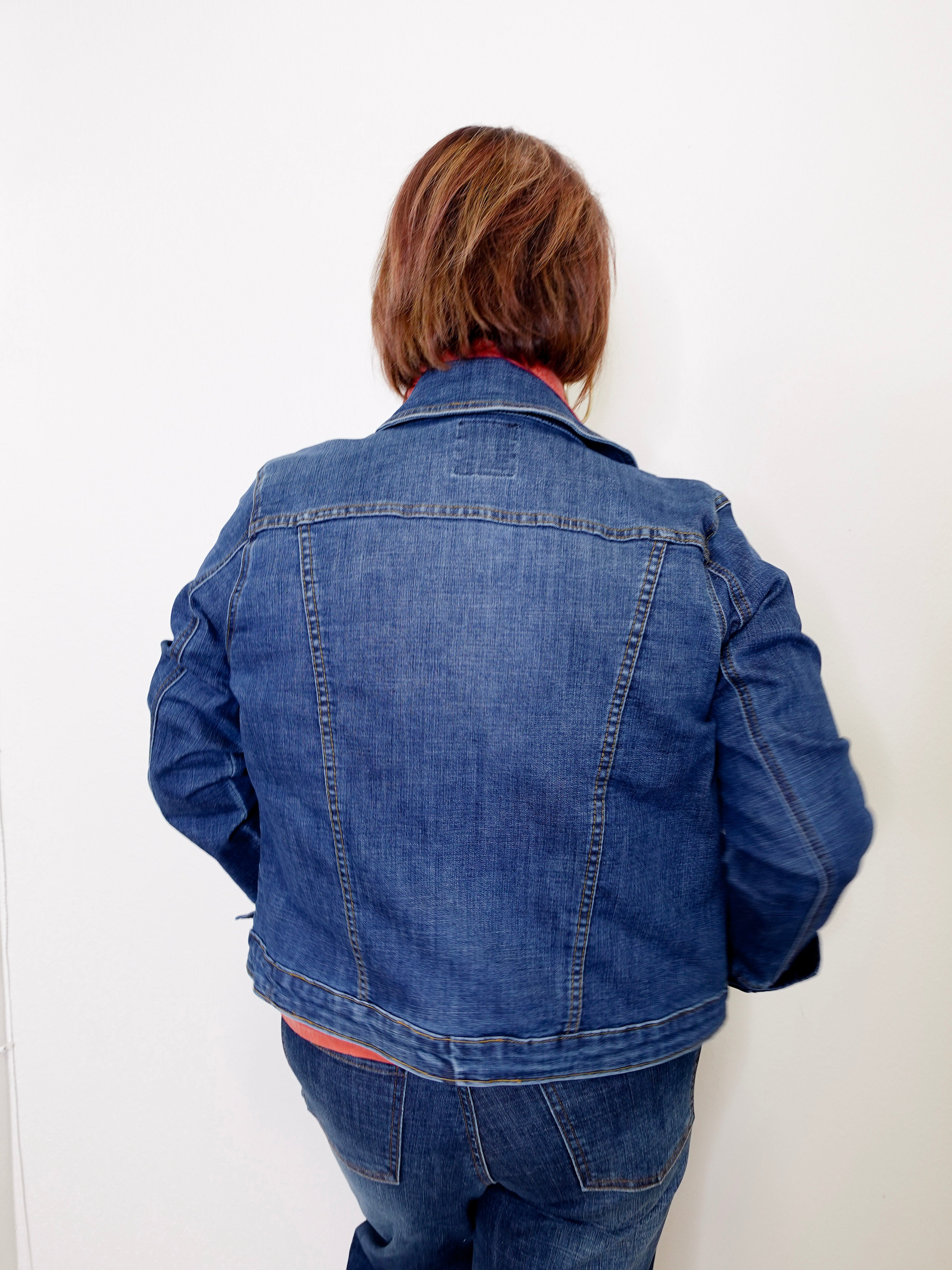 Person wearing a blue denim jacket against a white background