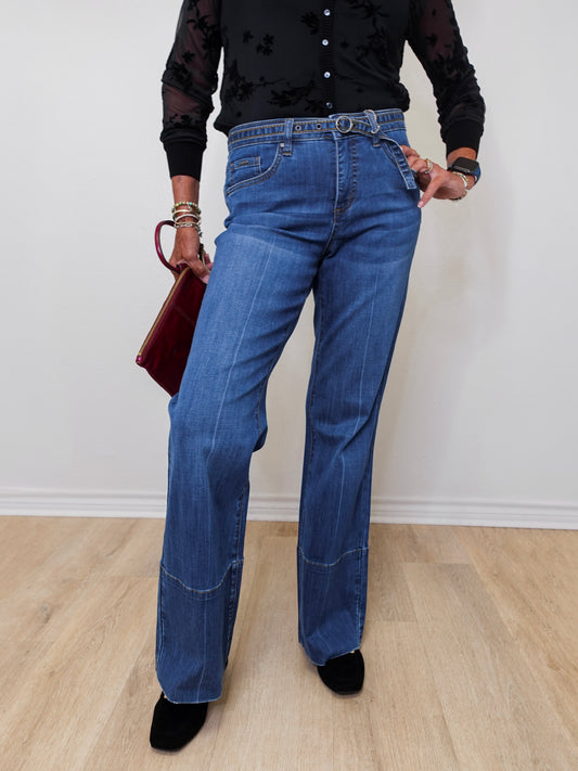 A woman modeling French dressing jeans the olivia bootleg jean against a white wall. 