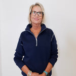 Woman wearing a navy blue pullover with a zipper against a white background