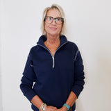 Woman wearing a navy blue pullover with a zipper against a white background