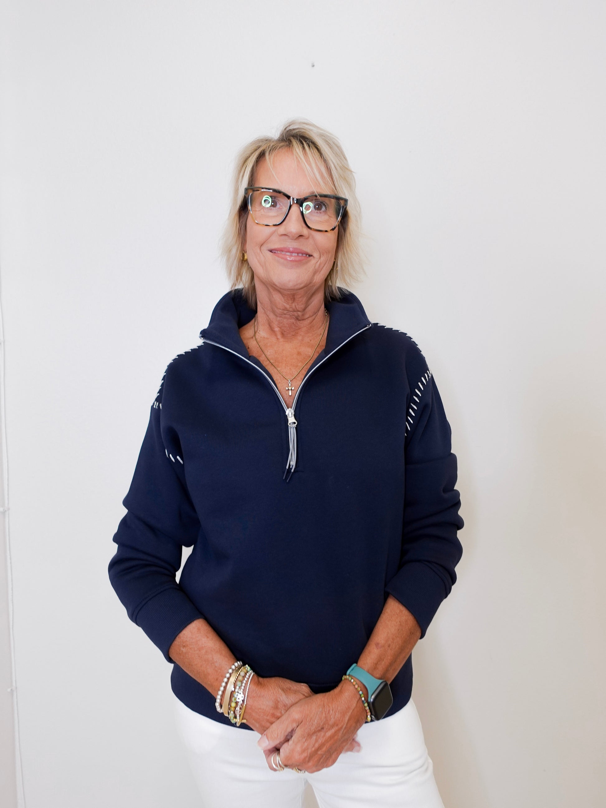 Woman wearing a navy blue pullover with a zipper against a white background