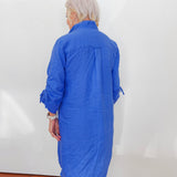 Person wearing a blue dress against a white wall