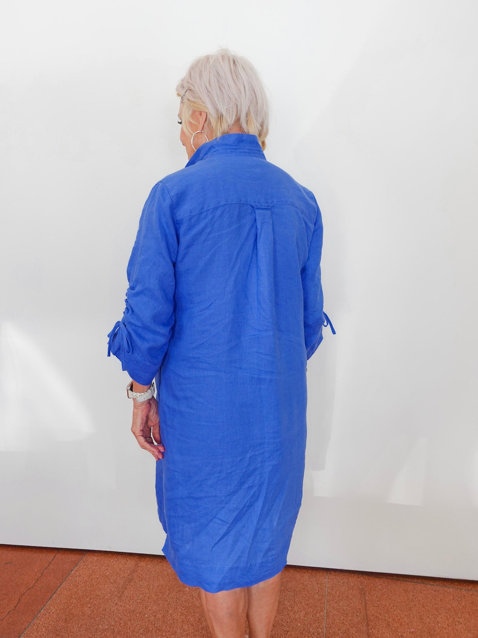 Person wearing a blue dress against a white wall