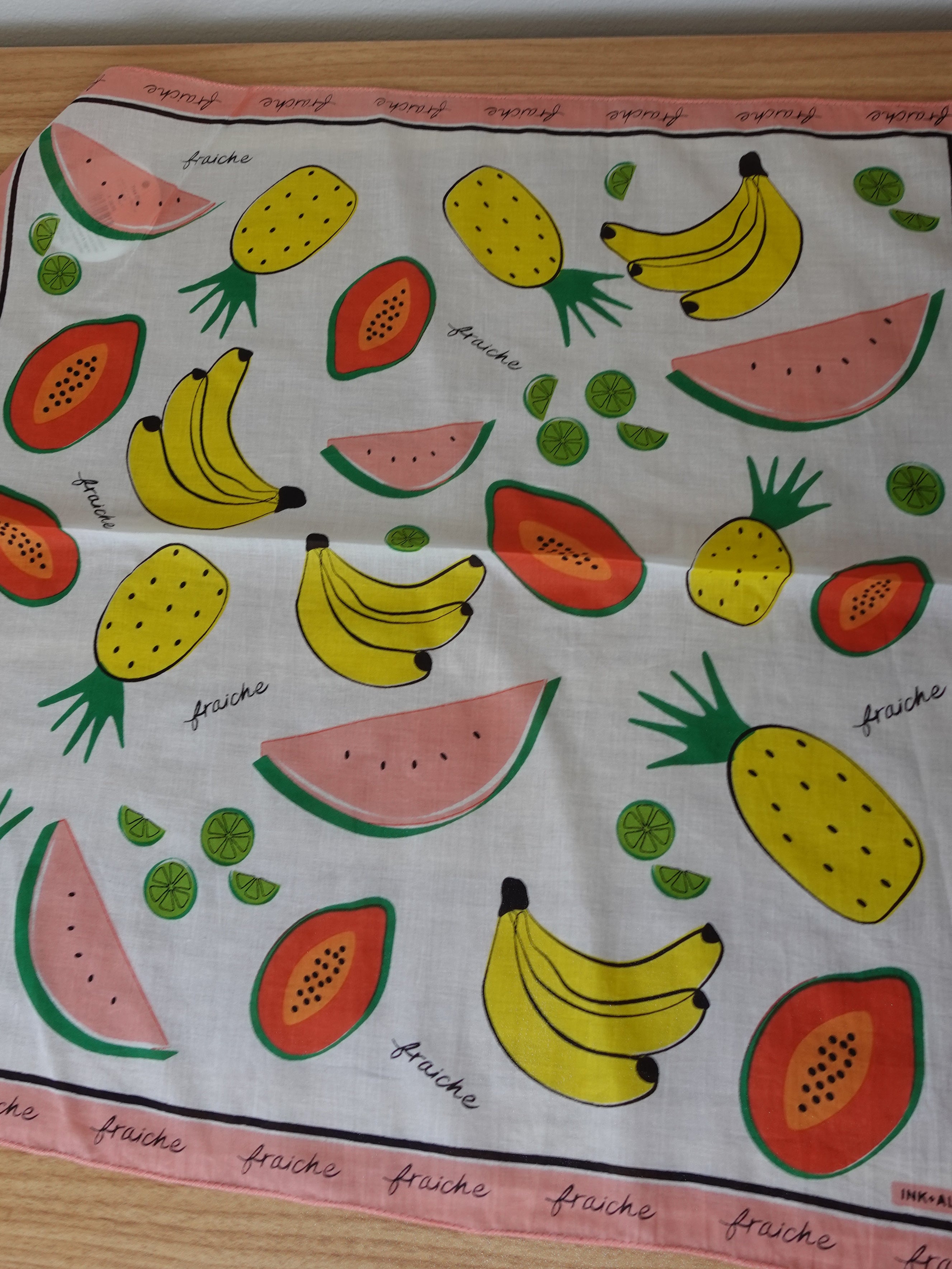 Fabric with colorful fruit pattern on a wooden surface