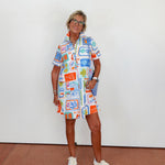 Person wearing a colorful patterned dress standing against a white wall.