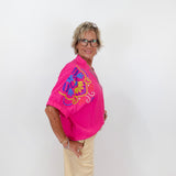 Person wearing a bright pink shirt with colorful design on a white background
