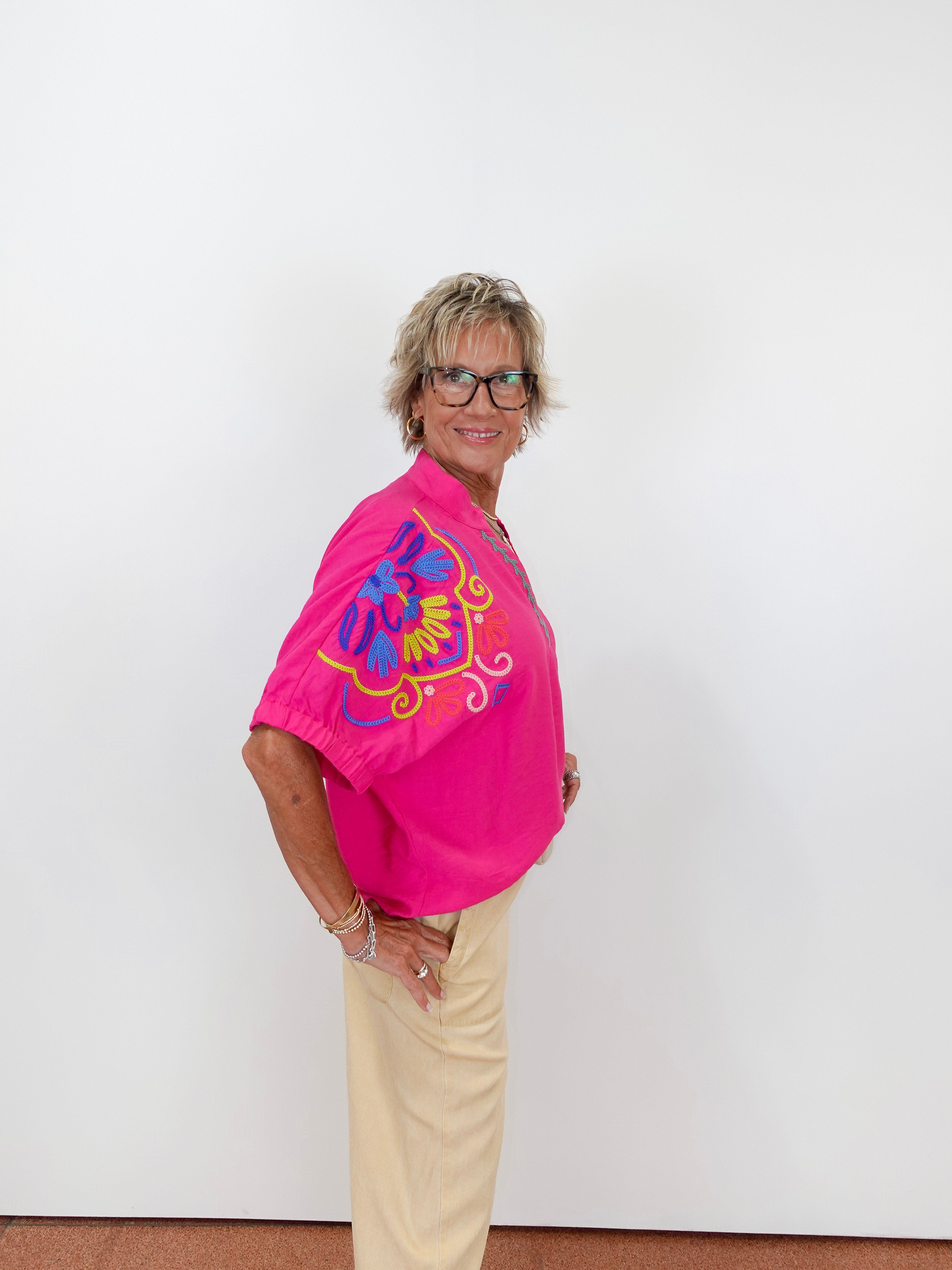 Person wearing a bright pink shirt with colorful design on a white background