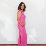 Woman wearing a pink striped dress standing against a white wall.