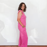 Woman wearing a pink striped dress standing against a white wall.