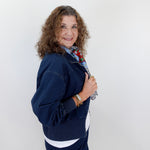 Woman wearing a navy blue outfit with a white shirt and floral scarf against a white background