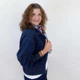 Woman wearing a navy blue outfit with a white shirt and floral scarf against a white background