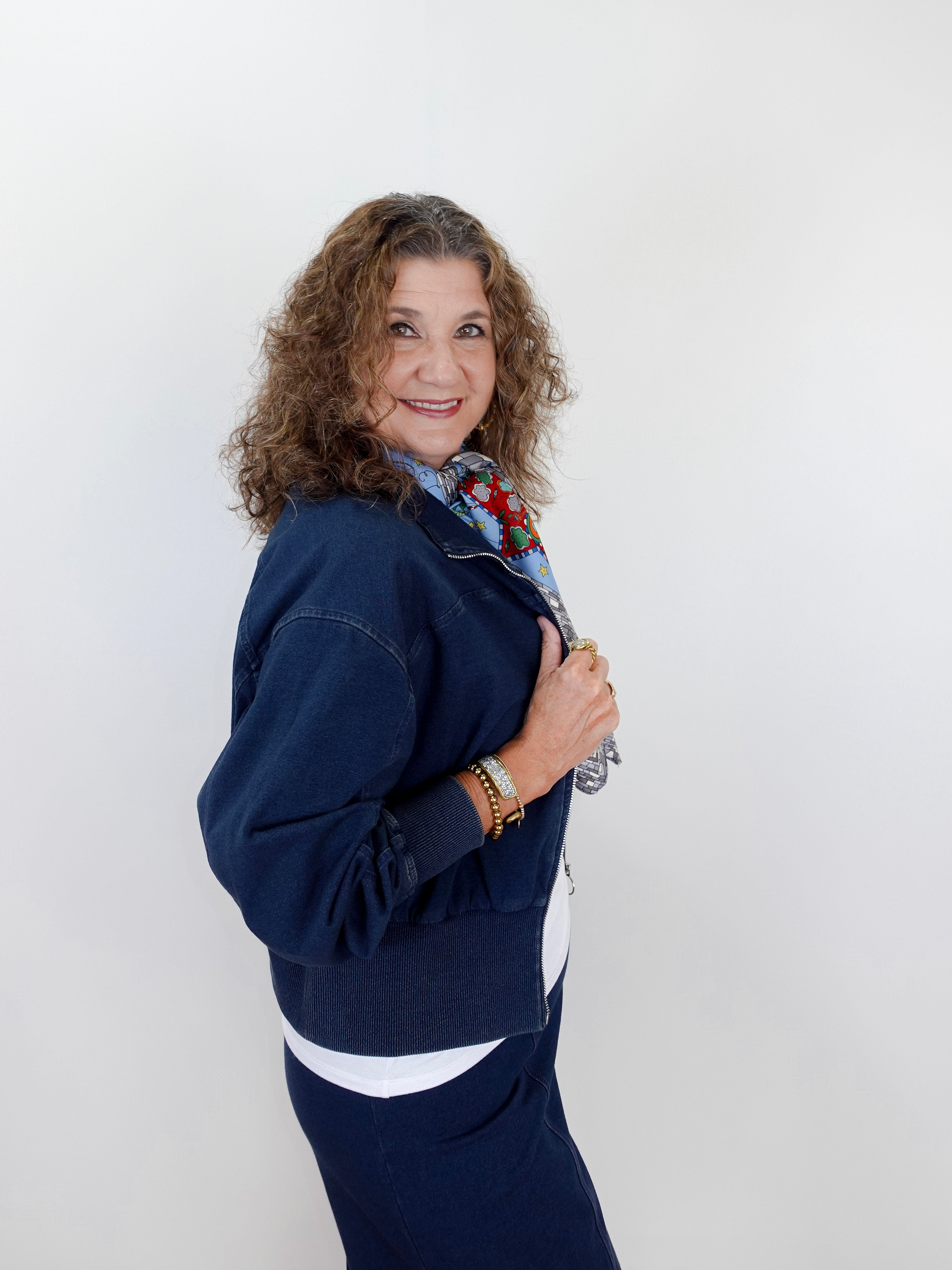 Woman wearing a navy blue outfit with a white shirt and floral scarf against a white background