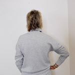 Person wearing a gray outfit against a white wall