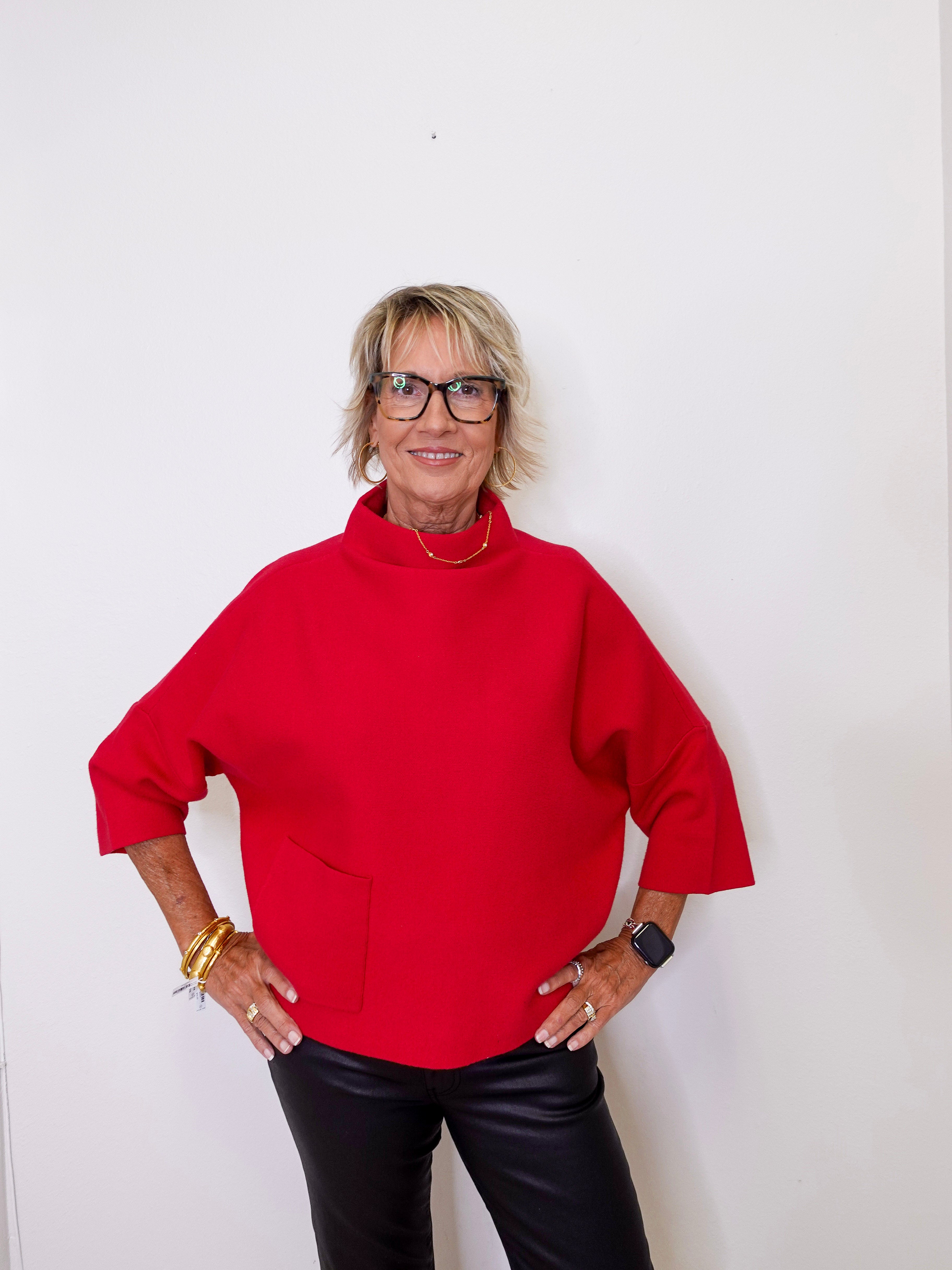 Person wearing a red sweater and black pants against a white background