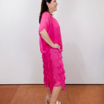 Woman wearing the Gail tiered ruffle dress in fuchsia with a flowy silhouette and layered ruffle details
