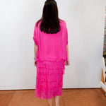 Woman wearing the Gail tiered ruffle dress in fuchsia with a flowy silhouette and layered ruffle details