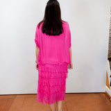 Woman wearing the Gail tiered ruffle dress in fuchsia with a flowy silhouette and layered ruffle details