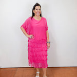 Woman wearing the Gail tiered ruffle dress in fuchsia with a flowy silhouette and layered ruffle details