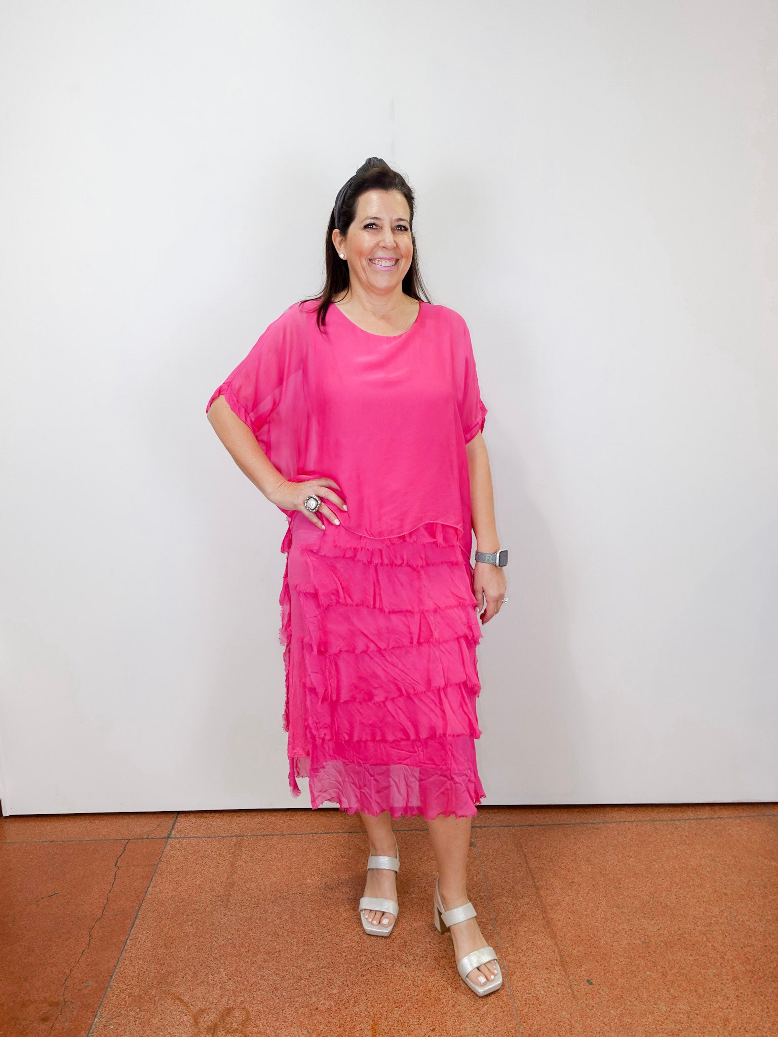 Woman wearing the Gail tiered ruffle dress in fuchsia with a flowy silhouette and layered ruffle details