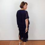 Woman wearing the Gail tiered ruffle dress in navy with a flowy silhouette and layered ruffle details.
