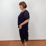 Woman wearing the Gail tiered ruffle dress in navy with a flowy silhouette and layered ruffle details.