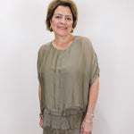 Woman wearing the Gail tiered ruffle dress in olive with a flowy silhouette and layered ruffle details.