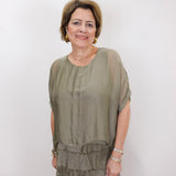 Woman wearing the Gail tiered ruffle dress in olive with a flowy silhouette and layered ruffle details.