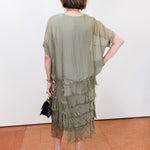 Woman wearing the Gail tiered ruffle dress in olive with a flowy silhouette and layered ruffle details.