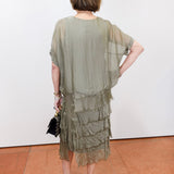 Woman wearing the Gail tiered ruffle dress in olive with a flowy silhouette and layered ruffle details.