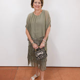 Woman wearing the Gail tiered ruffle dress in olive with a flowy silhouette and layered ruffle details.