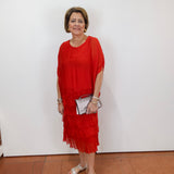 Woman wearing the Gail tiered ruffle dress in red with a flowy silhouette and layered ruffle details.