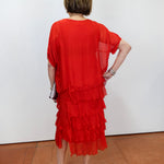 Woman wearing the Gail tiered ruffle dress in red with a flowy silhouette and layered ruffle details.