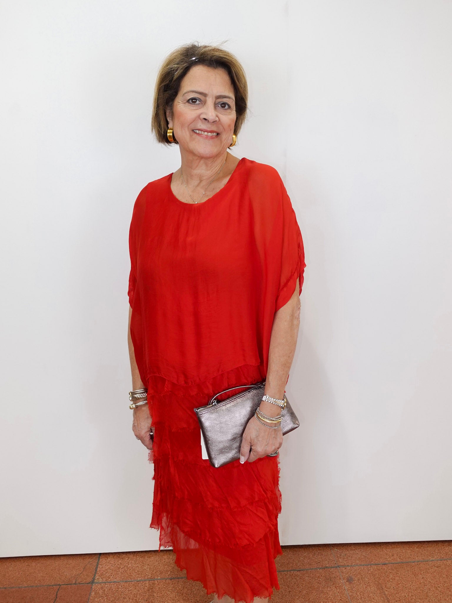 Woman wearing the Gail tiered ruffle dress in red with a flowy silhouette and layered ruffle details.